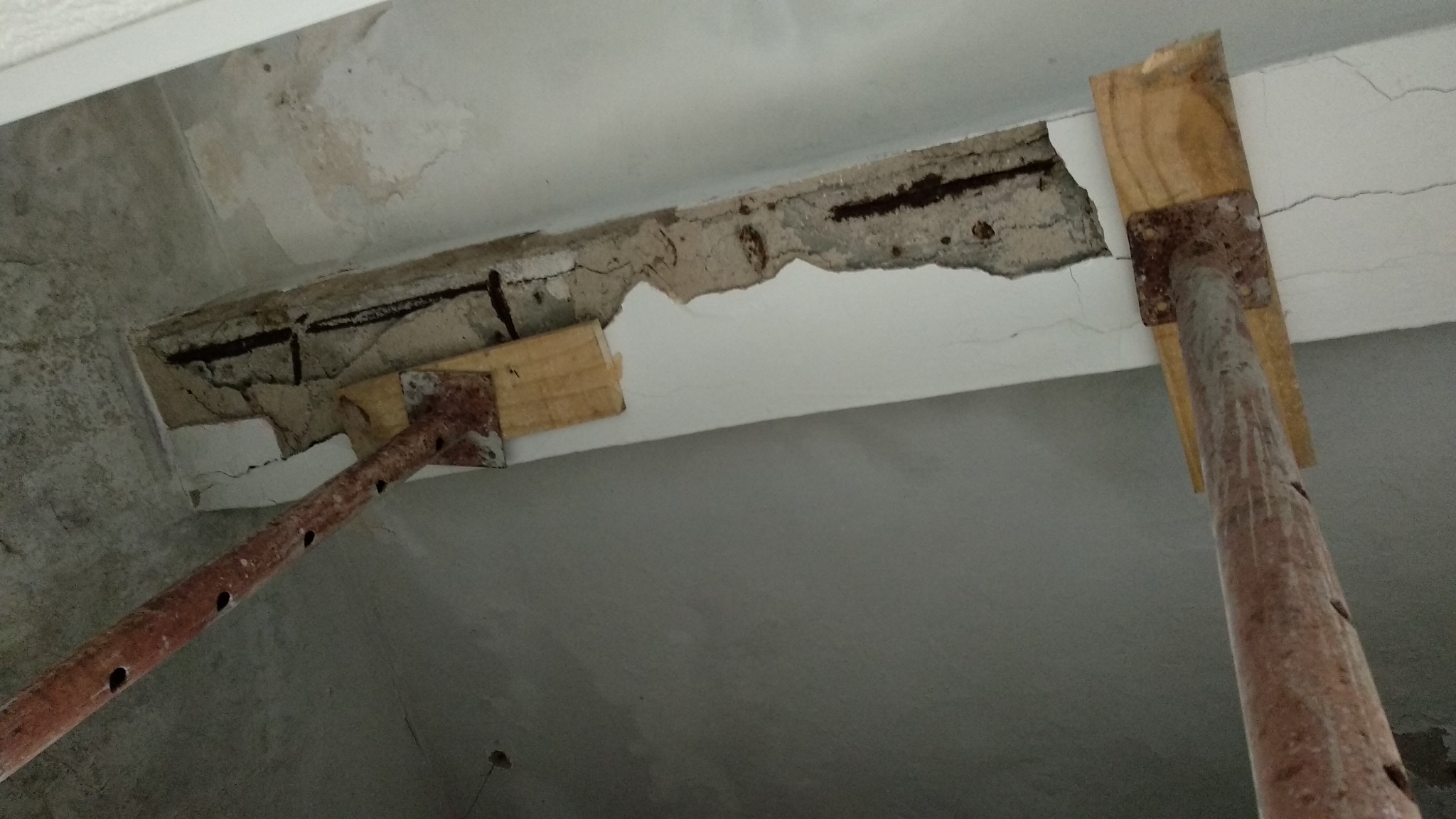 Elemento de concreto com fissuras, desprendimento do cobrimento e armadura exposta.